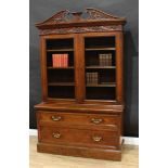 A Victorian oak library bookcase, swan neck pediment and deep frieze carved in relief with Tudor