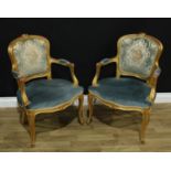 A pair of Louis XV style giltwood fauteuils, flower crestings, stuffed over upholstery, cabriole
