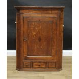 A George III oak and mahogany splay fronted wall hanging corner cupboard, rectangular panel door