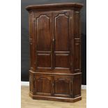 A 19th century oak floor-standing splay-fronted corner cupboard, outswept cornice above a pair of