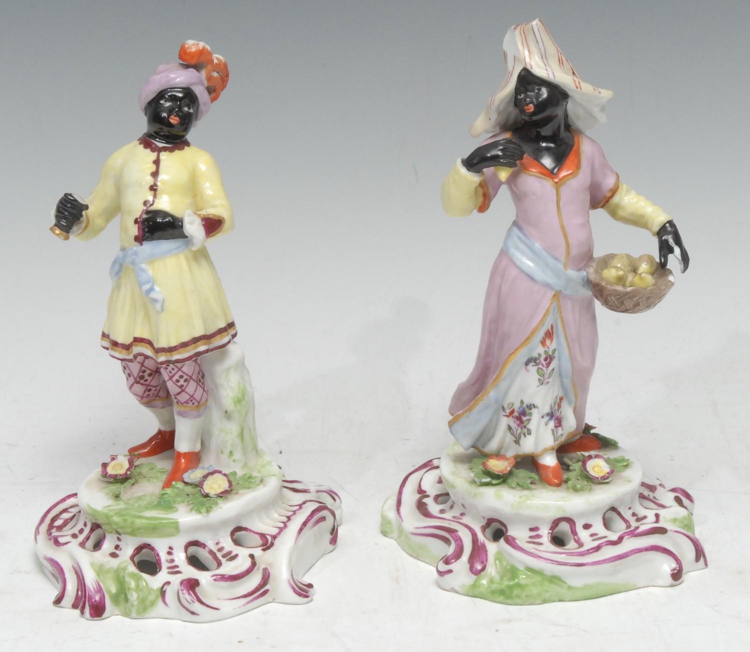 A pair of Continental figures, of Blackamoors, in traditional dress, pierced bases, 17.5cm high, c.