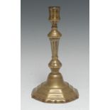 An early 18th century French brass candlestick, of seamed construction, knopped tapered stem, shaped