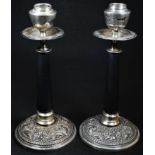 A pair of Burmese silver candlesticks, ovoid sconces, dished drip pans, bowed cylindrical columns,