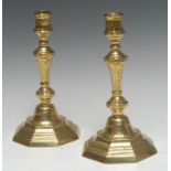 A pair of early 18th century French brass octagonal candlesticks, chased with flowerheads, stiff