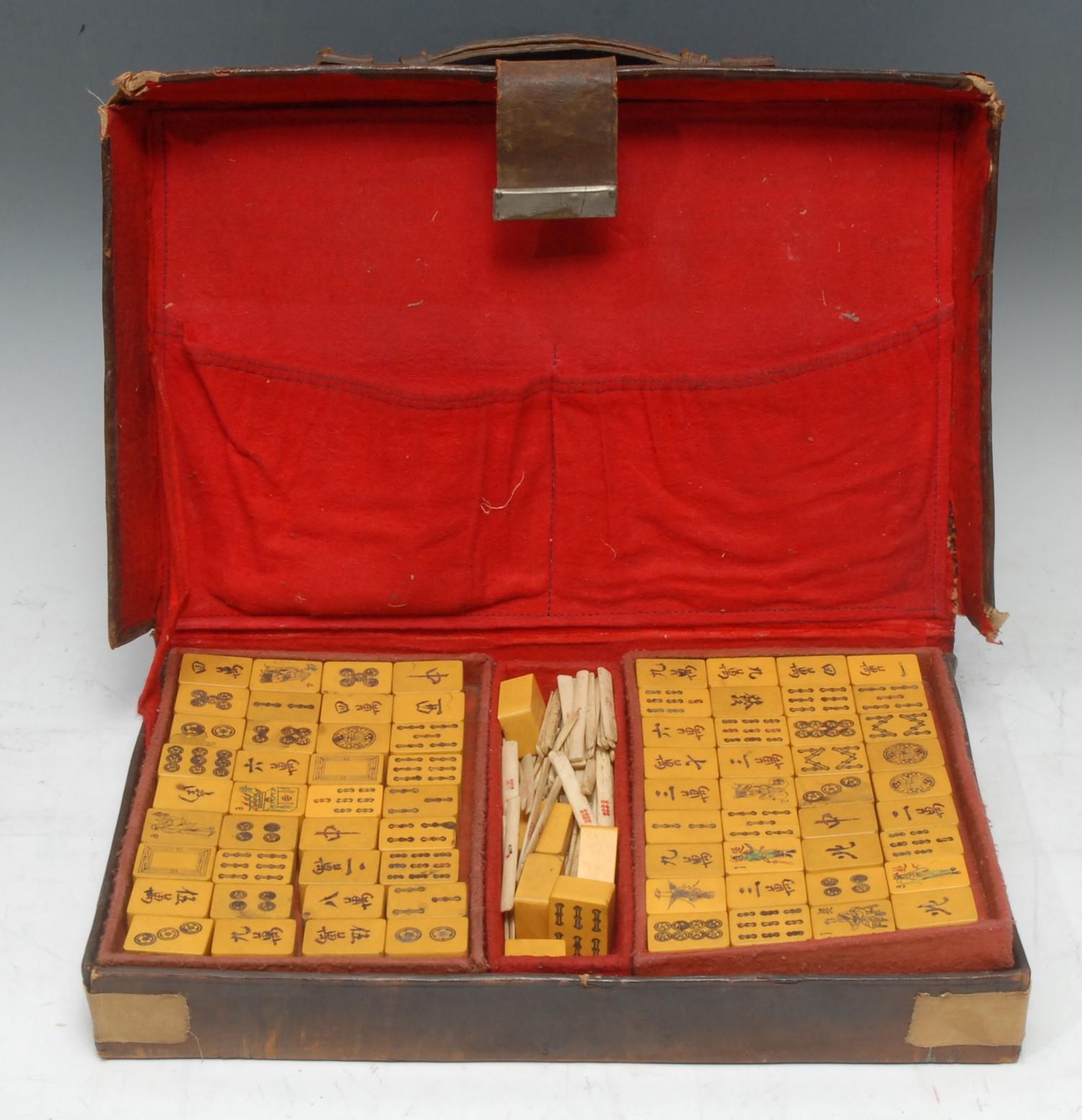 A Chinese mahjong set, one hundred and forty four tiles, tan leather case, 36cm wide overall,