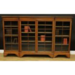An early 20th century oak break-centre low library bookcase, moulded top above two pairs of glazed