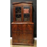 A Biedermeier flame mahogany secretaire bookcase, pointed architectural cresting above a pair of