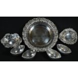 A late Victorian silver shaped circular dish, the outswept border repoussé chased with flowers and
