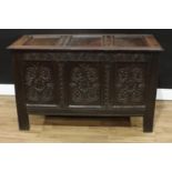A Charles II oak three panel blanket chest, hinged top, the front carved with leafy lunettes,