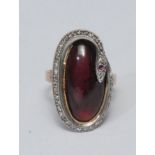 A large diamond and red stone snake ring, purply red cabochon center surrounded by a diamond