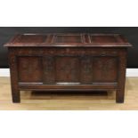 An early 18th century oak three panel blanket chest, hinged top, the front carved with leafy