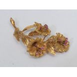 A mid 20th century floral spray brooch, triple trumpet spray each inset with four pinky red ruby