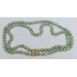 A pale jade green two strand bead necklace, two uniform strands of multi tone green beads, united by