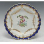A Worcester shaped circular plate, painted with two exotic birds in a landscape surrounded by gilt