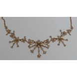 An Edwardian gold coloured metal and seed pearl necklace, formed as a fringe of flowerheads and