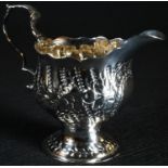 An early George III silver pedestal cream jug, chased with flowers and spiral flutes, acanthus