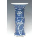 A Chinese Gu-shaped beaker vase, painted in underglaze blue with flowering prunus, central girdle,