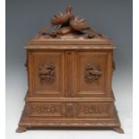 A Black Forest desk top writing and stationery cabinet, hinged cover above a pair of doors carved