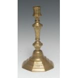 An early 18th century French brass octagonal candlestick, chased with flowers, stiff leaves and