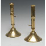 A matched pair of early 18th century brass ejector candlesticks, flared sconces, domed shaped