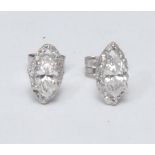 A pair of navette diamond stud earrings, quarter claw set above textured collar, total estimated