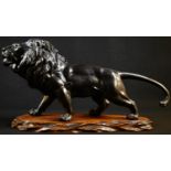 Japanese School (Meiji period), a dark patinated bronze, of a lion, prowling, 47cm long,hardwood