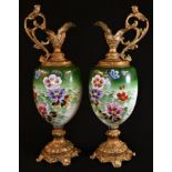 A pair of Rococo Revival gilt-metal mounted ewers, the ovoid ceramic ewers painted with country