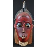 Tribal Art - a Guro mask, lofty coiffure, stylised scarified features decorated in tones of red,
