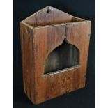 A 19th century vernacular pine candle box, of primitive construction, pierced ogee bell-shaped