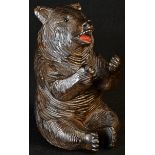 A Black Forest novelty inkwell, carved as a bear, seated, smiling, glass eyes, painted mouth, hinged