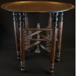 A Middle Eastern table, the circular brass top chased in the Islamic taste with calligraphy and