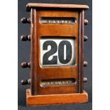 An early 20th century mahogany perpetual desk calendar, oversailing top above glazed apertures for