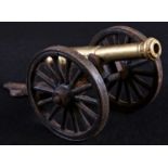 A brass and cast iron desk model cannon, 13cm barrel, spoked wheels, 20.5cm long overall