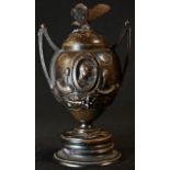 A 19th century brown patinated bronze, cast with portrait ovals, butterfly finial, belge noir