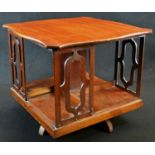 An Edwardian mahogany serpentine table top revolving bookcase, tracery end supports, downswept legs,