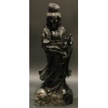 A large Chinese obsidian figure, carved as Guanyin holding a ruyi sceptre and a pearl, 94cm high,