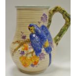 A Clarice Cliff jug moulded in relief with a parrot & foliage, naturalistic handle, ribbed