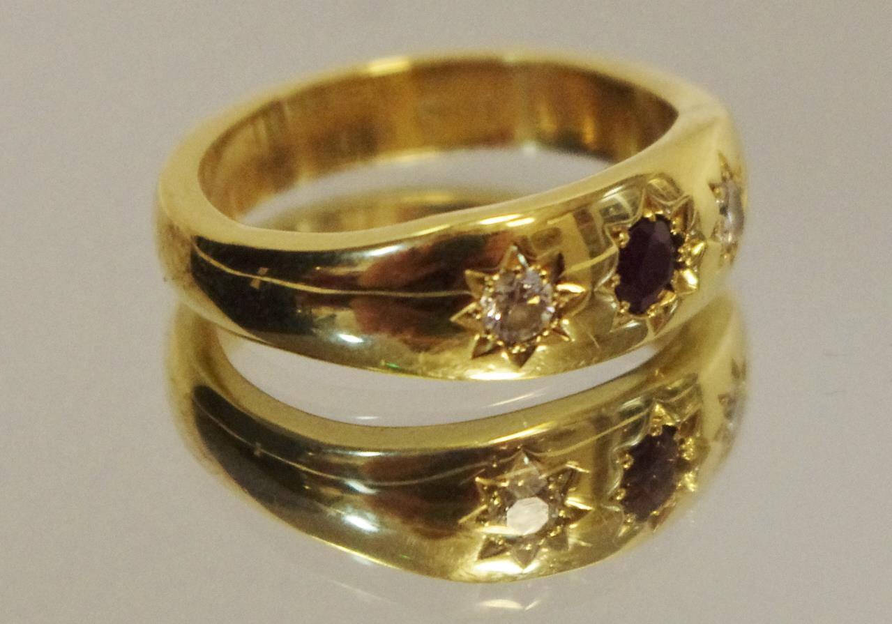 An 18ct gold ring set with central round ruby and flanked by two round diamonds, size M, 7.4g