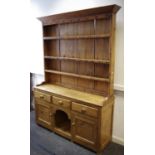 A Victorian pine dresser shelving and cup hooks to top, three short drawers over central recess