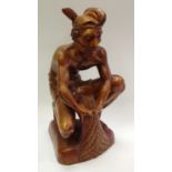A mid 20th century Javanese carved wooden figure, pulling in the catch, he crouches griping his