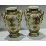 A pair of Noritake ovoid two handled vases, decorated with shield shped cartouches iwth cattle,