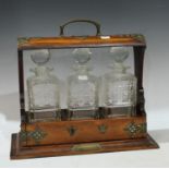 A Victorian oak tantalus, comprising three glass decanters with stoppers