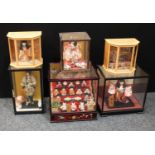 A collection of 20th century Japanese dolls and figures displayed in glazed cases including a