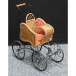 A Victorian style wrought iron and wicker pram.