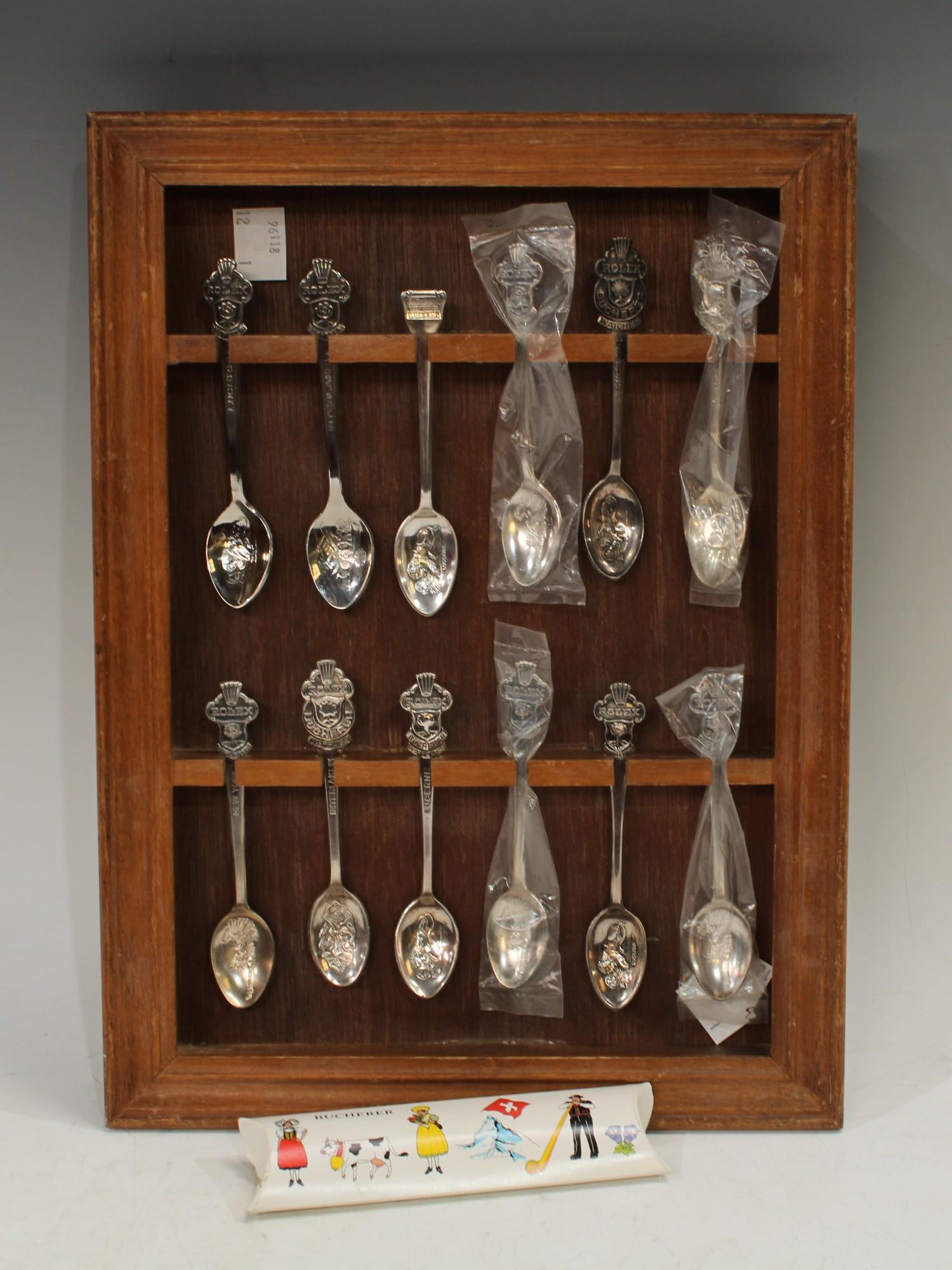 A set of thirteen Rolex base metal teaspoons, a wooden spoon rack