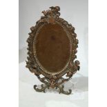 A Victorian 'bronzed' easel back oval mirror, with cherubs