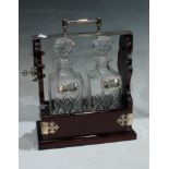 A 20th century two bottle tantalus, each decanter with hallmarked silver labels, Brandy and Whisky
