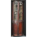 A 19th century mahogany floorstanding bow fronted corner display cabinet, dentil cornice above a