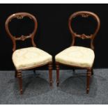 A pair of Victorian mahogany side/dining chairs, shaped back, stuffed-over upholstery, tapered