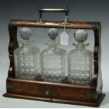 A Victorian oak tantalus with three cut glass decanters